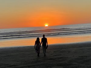 romantic couple walking on playa guiones at sunset, nosara, costa rica