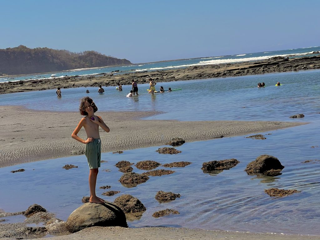 families playing in tide pools at playa guiones, nosara, costa rica